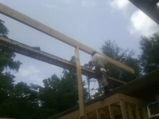 Carpenter setting a ridge beam over a new addition frame — Ice Dam Removal by Roofing Brothers in Saint Joseph