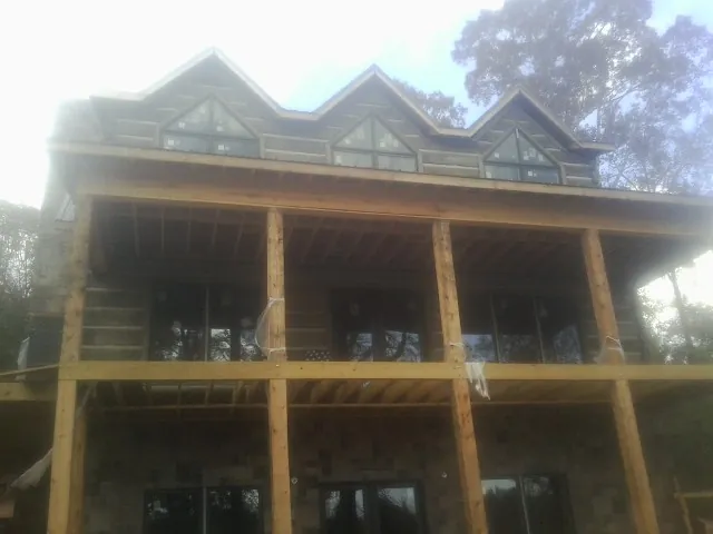 Dormers and porch framing on a large log home under construction — Roof Coating work by our crew in Saint Joseph