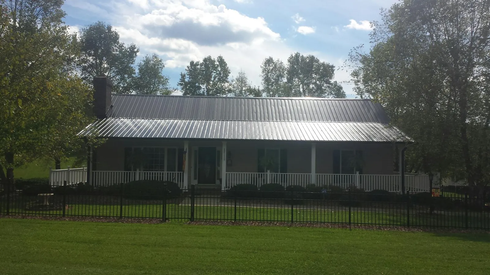 Gray metal roof on a brick ranch with a full width front porch — Gutter Guard Installation work by our crew in Saint Joseph